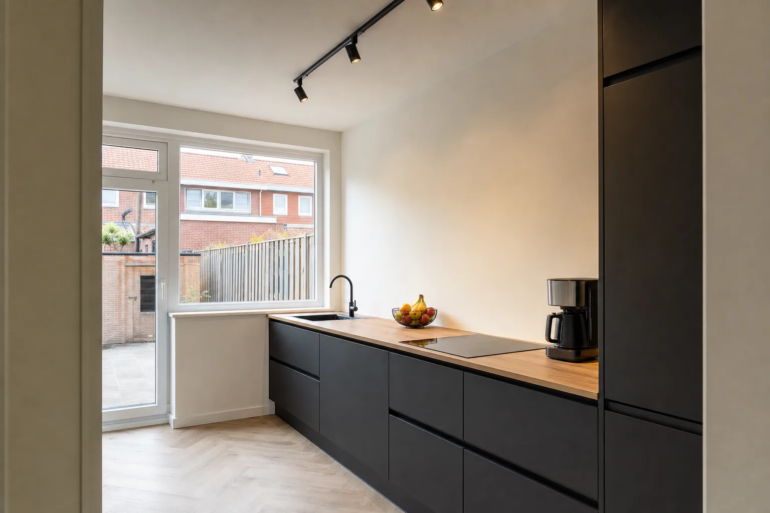 Opgeleverde keuken in mat zwart met houten werkblad en visgraatvloer in een Nederlandse woning