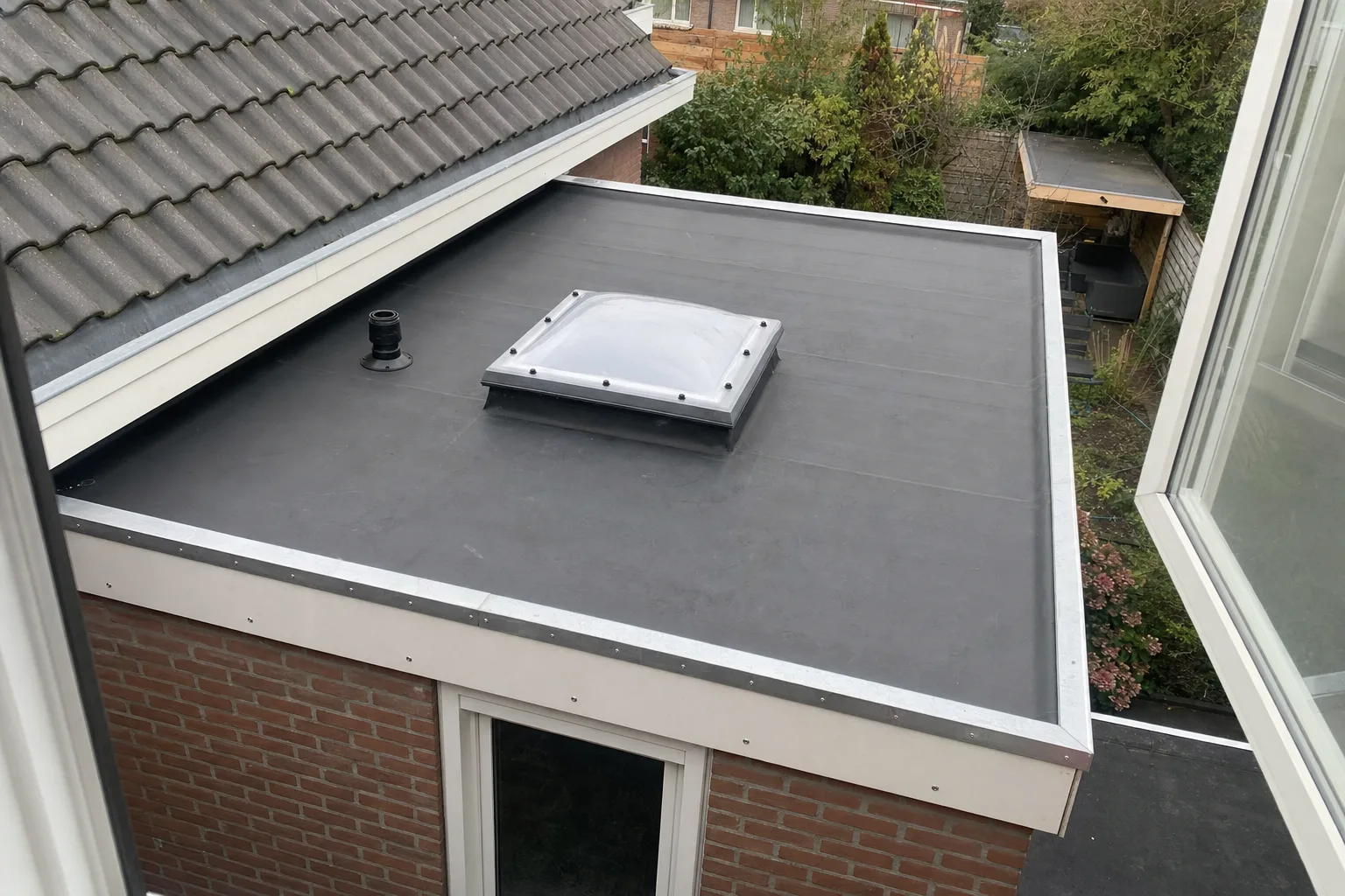 Net vernieuwd plat dak met EPDM en lichtkoepel op een aanbouw