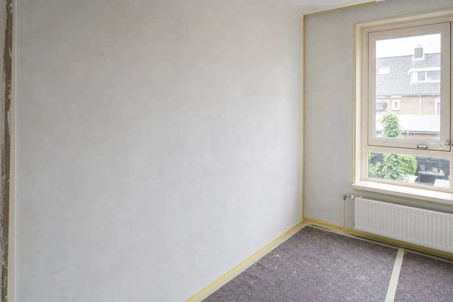 Muur met gevulde scheuren en afgedekte vloer, klaar om te stucen