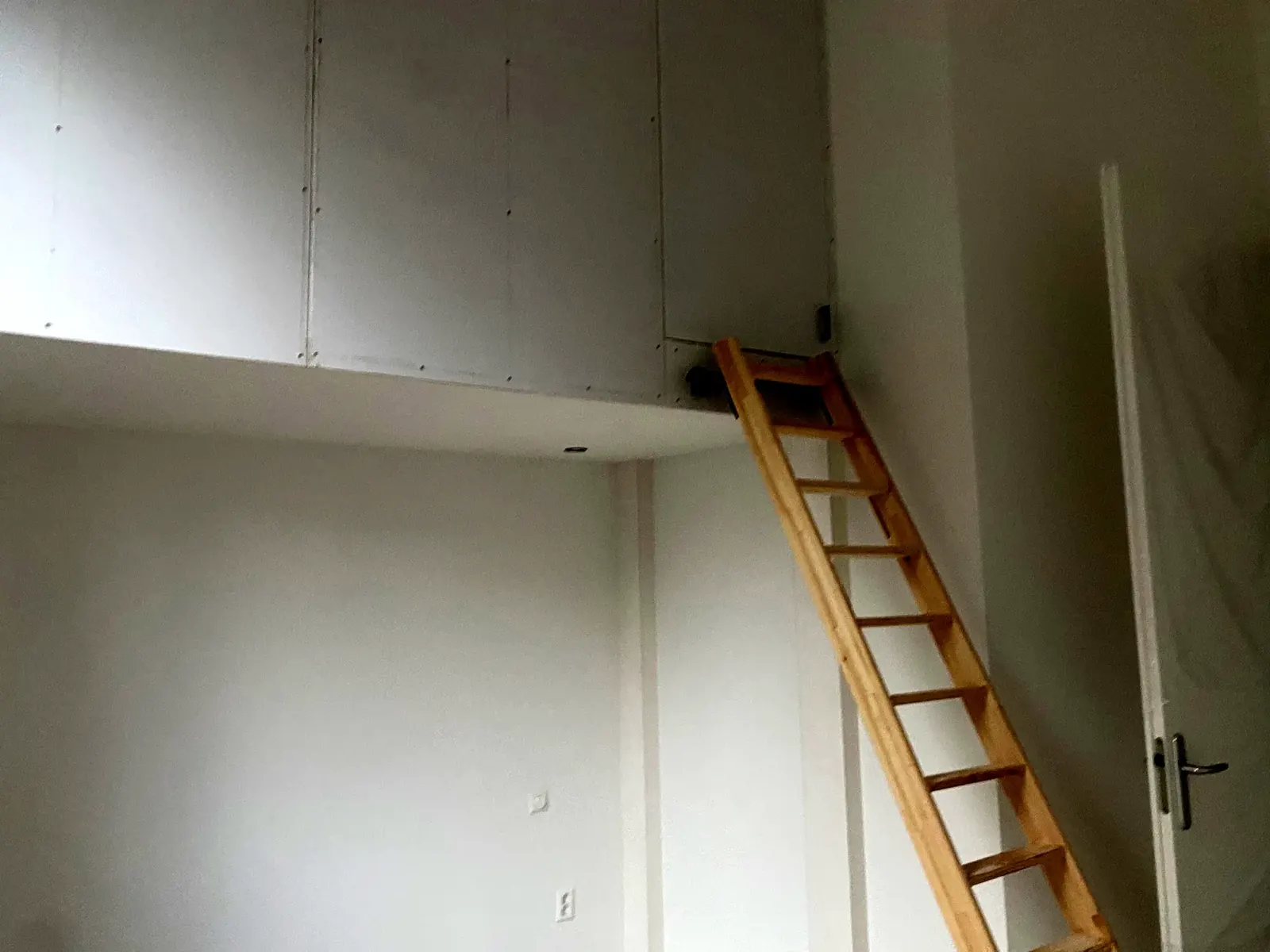 Houten trap naar een vliering in een lichte kamer