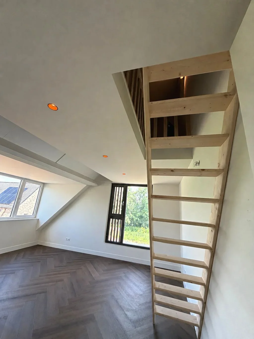 Vaste houten trap naar de vliering in een lichte zolderkamer