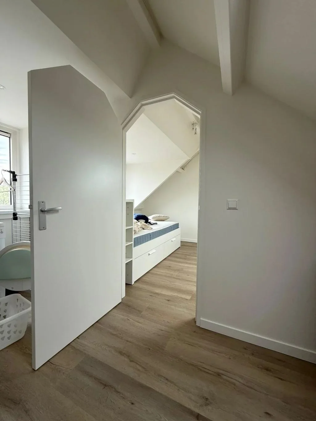 Zolder opgedeeld in twee kamers met een deurkozijn in de schuine wand