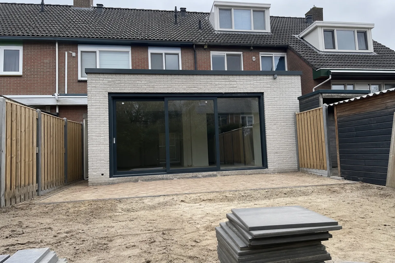 Aanbouw aan de achtergevel van een woning met tuin, binnen de vergunningvrije diepte