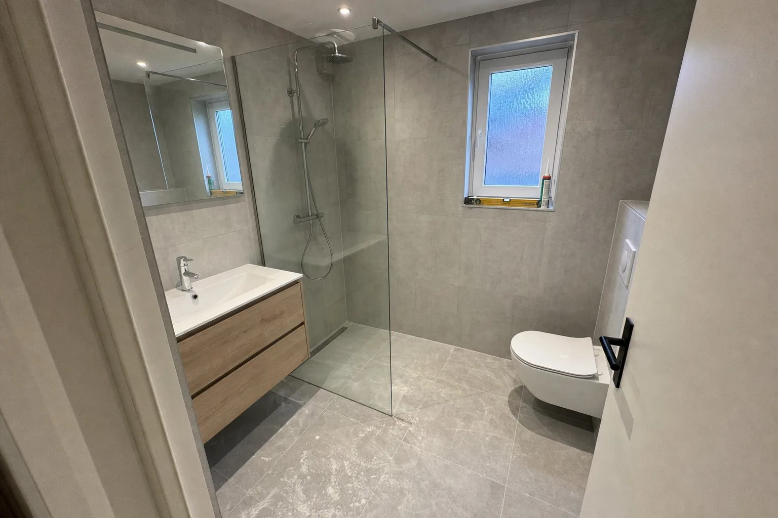 Gerenoveerde witte badkamer met inloopdouche en strakke kitnaden