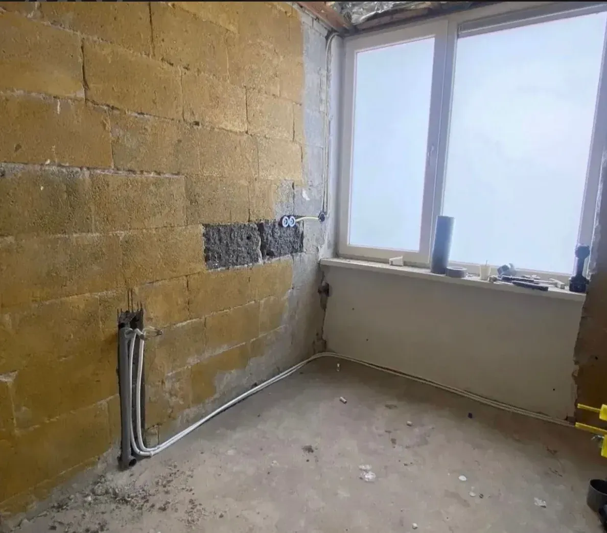Badkamer voor de renovatie met kale muren en leidingen