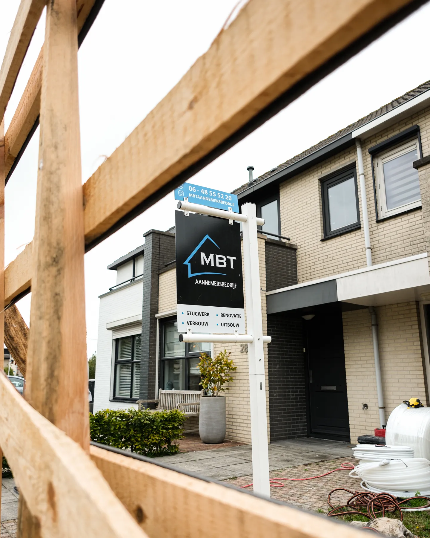 Bouwbord van MBT bij een woning met steigerhout op de voorgrond