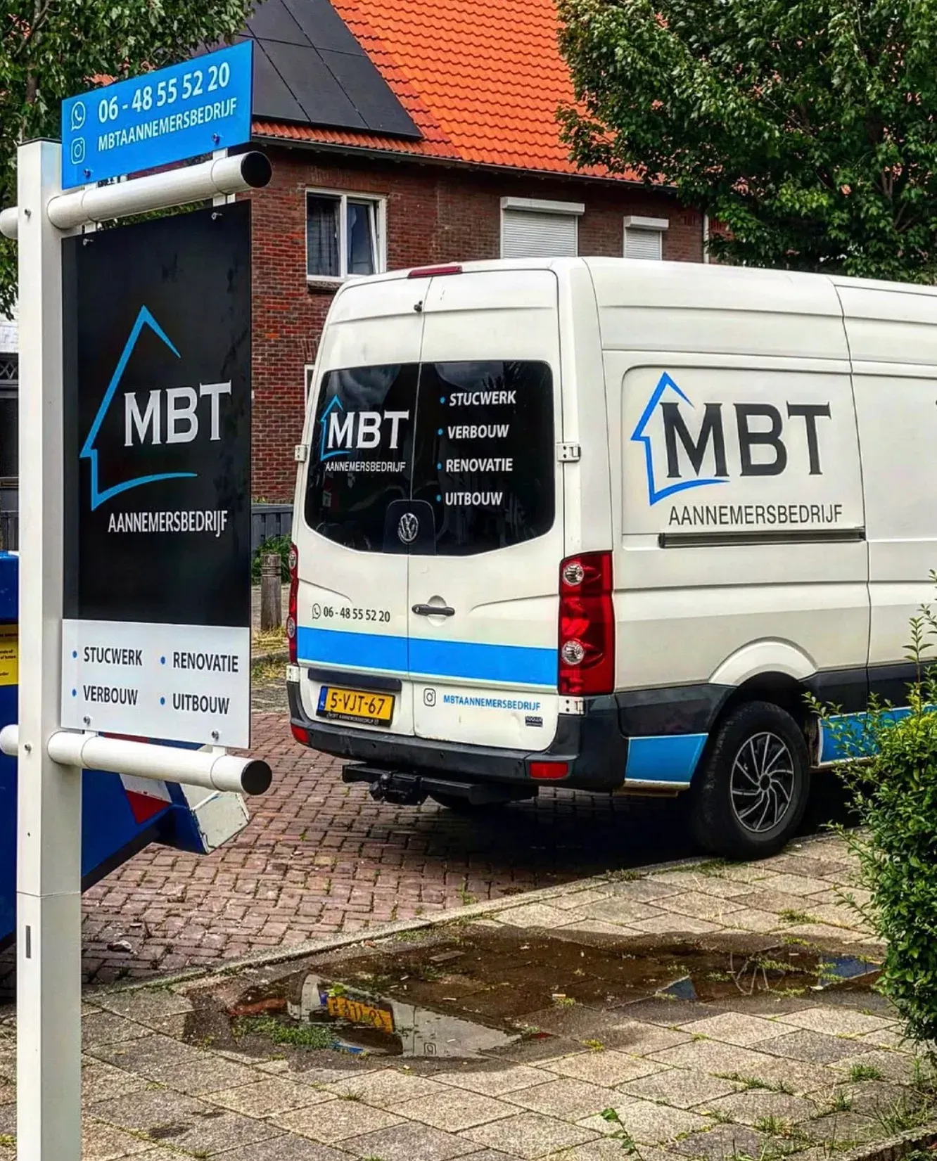 Bedrijfsbus en bouwbord van een aannemer bij een woning