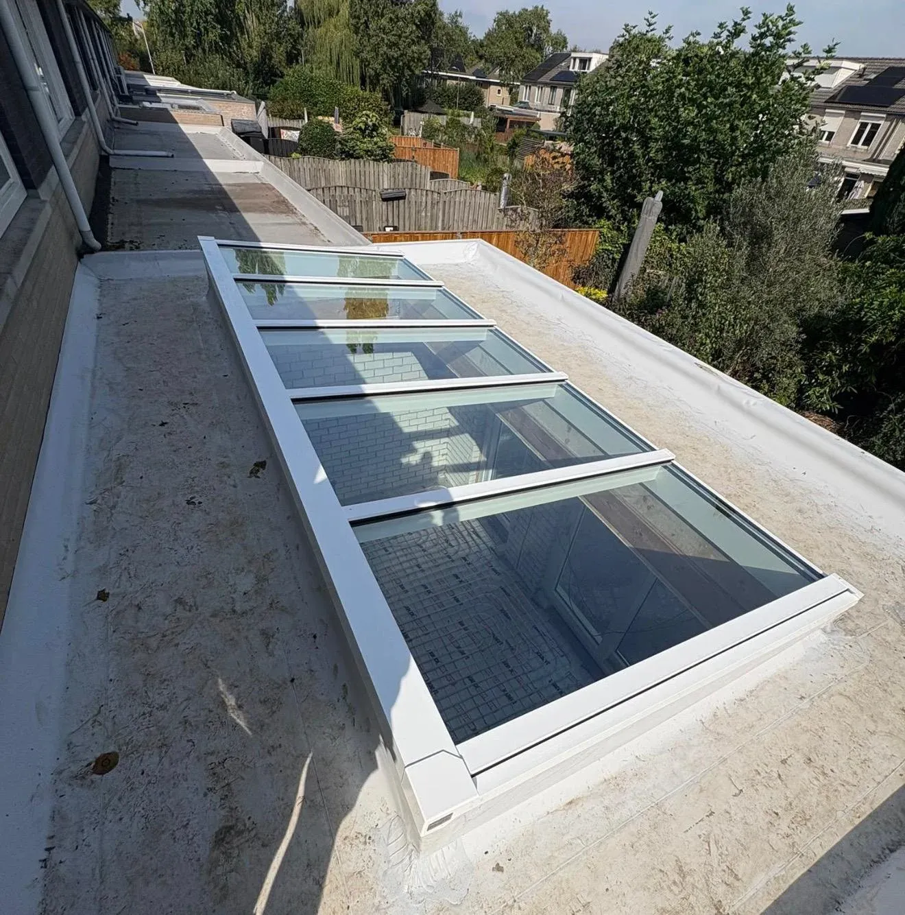Plat dak van een aanbouw met lichtstraat, van bovenaf gezien