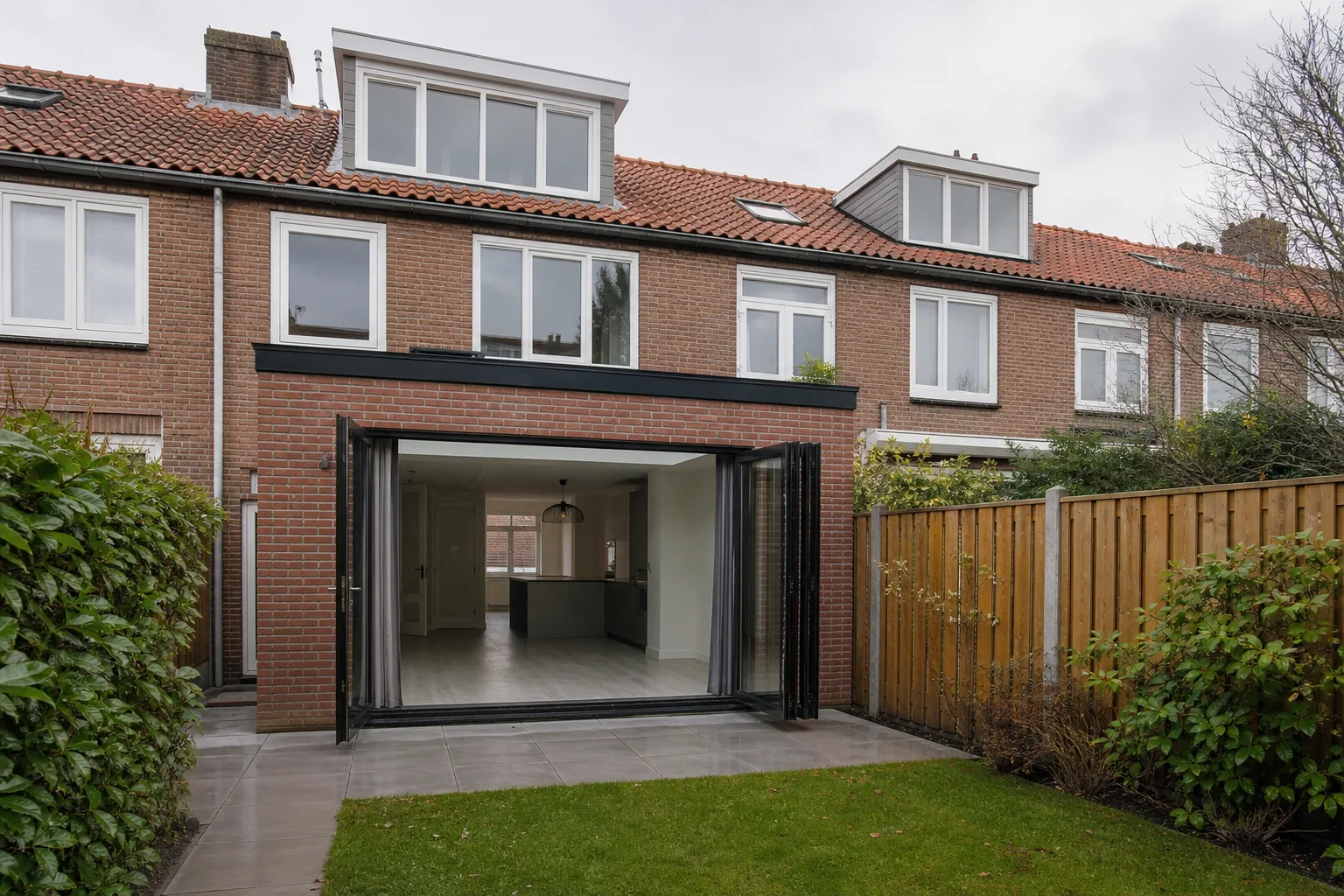 Uitbouw aan de achtergevel van een rijtjeshuis met tuin